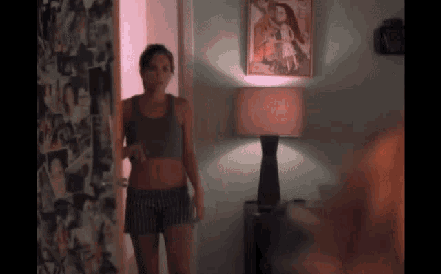 a woman in a tank top and shorts is standing in a room