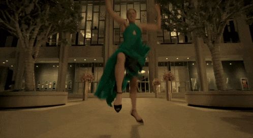 a woman in a green dress is running towards a building