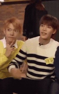 two young men are sitting next to each other and one of them has a name tag that says " taeil " on it