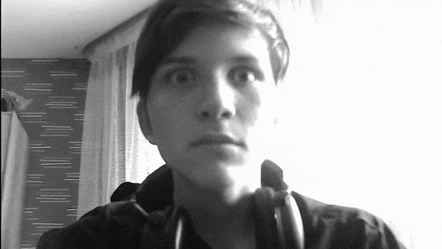 a black and white photo of a young man wearing headphones and looking at the camera .