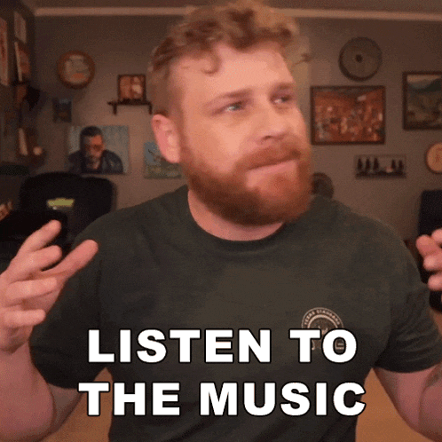 a man with a beard wearing a black shirt that says listen to the music