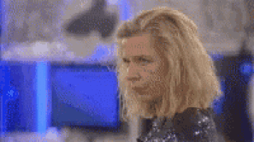 a woman with blonde hair is standing in front of a microphone and looking at the camera .
