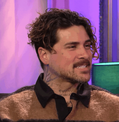 a man with curly hair and a beard has a tattoo on his face that says whale