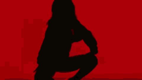 a silhouette of a woman kneeling down on a red background .
