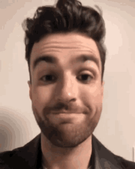 a man with a beard is making a funny face with his eyes closed .