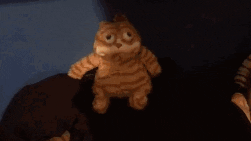 a stuffed cat is standing next to a robot in a dark room