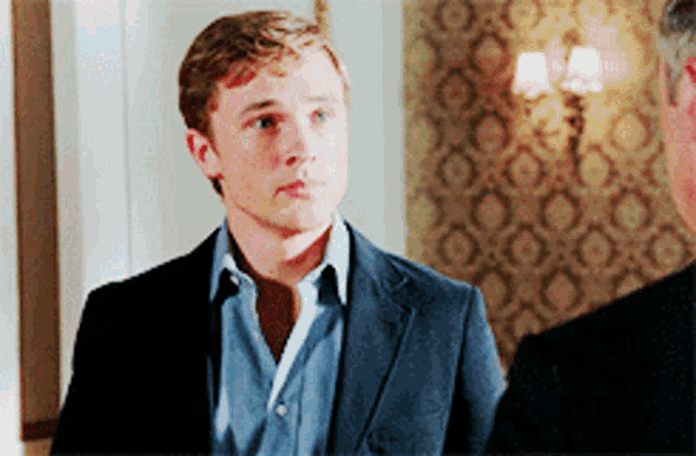 a man in a suit and a blue shirt is standing next to another man