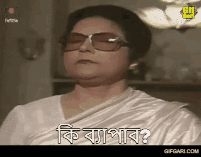 a woman wearing sunglasses and a white shirt is asking a question in a foreign language