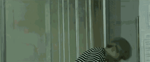 a man in a striped shirt is laying on his back in a room with a white shirt on .