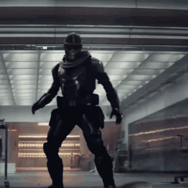 a man in a black armor is standing in a hallway