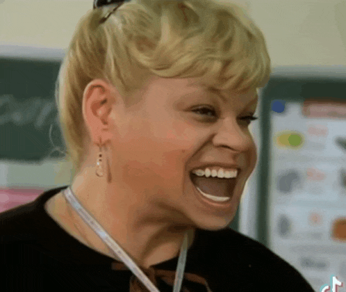 a woman with a lanyard around her neck is laughing with her mouth open