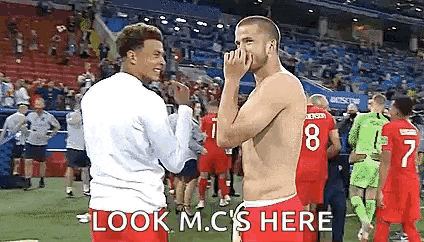 two soccer players are standing next to each other on a soccer field .