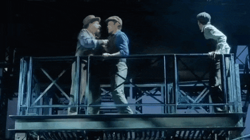 a group of men are standing on a balcony talking to each other