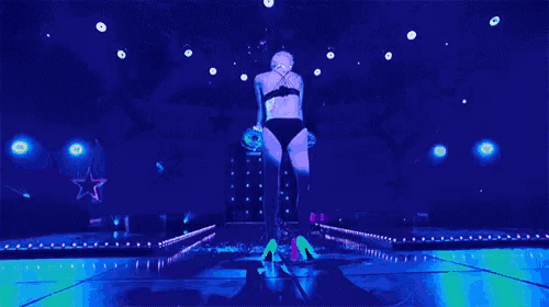 a woman in a black bra and thigh highs is dancing on a stage