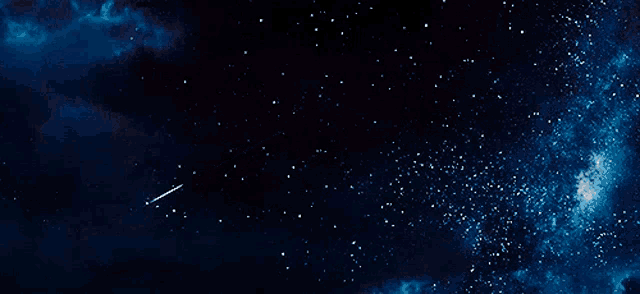 a shooting star is flying through a starry night sky .