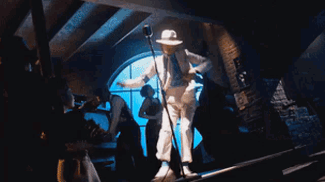 a man in a white suit is dancing in front of a crowd of people