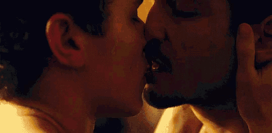 a man and a woman are kissing in a dark room in a close up of their faces .