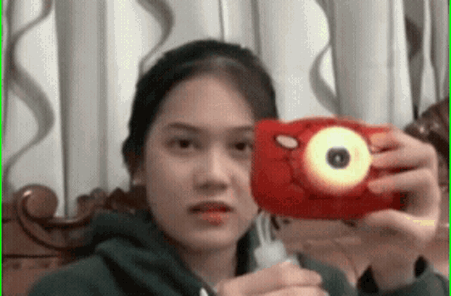 a girl is taking a picture of herself with a red camera .