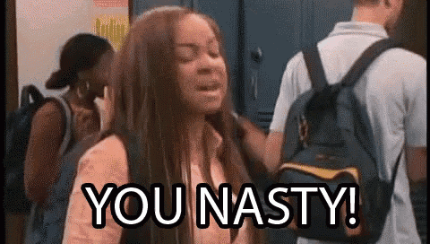 a girl with a backpack is standing in a hallway with other people and says `` you nasty '' .