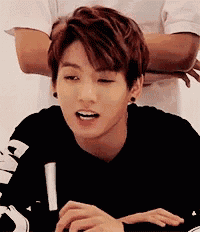 a young man with red hair is sitting at a table with his arms crossed and his mouth open .