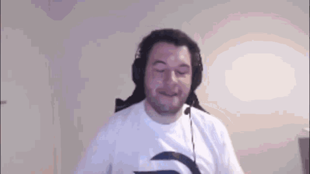 a man wearing headphones and a white shirt is standing in front of a camera .