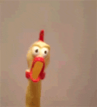 a rubber chicken with a surprised look on its face is standing in front of a white wall .