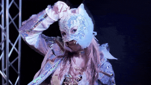 a woman is wearing a cat mask and gloves while standing on a stage .