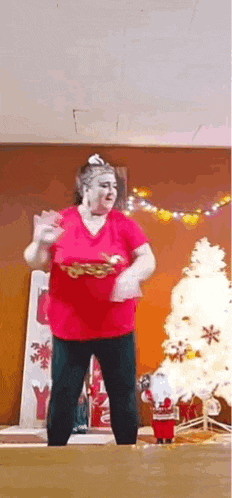 a woman is dancing in front of a christmas tree .