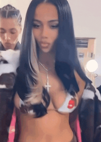 a woman in a bikini top with a cross necklace is standing next to another woman in a room .