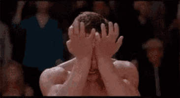 a man without a shirt is making a funny face with his mouth open in front of a crowd .