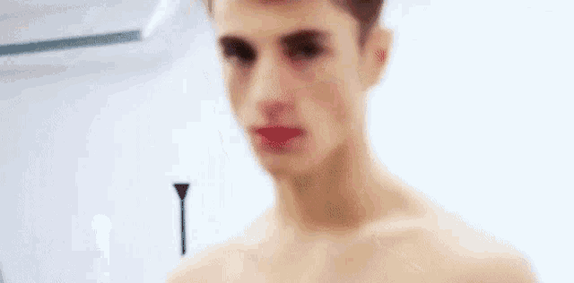 a young man without a shirt is looking at the camera and making a funny face .