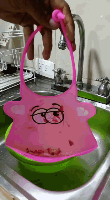 a person holding a pink bib over a sink