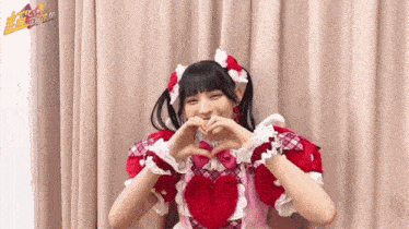 a girl is making a heart shape with her hands .