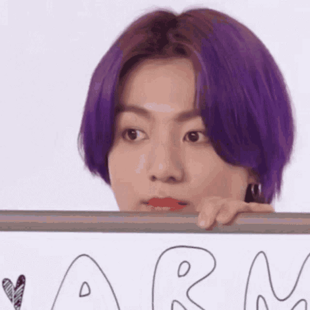 a close up of a person with purple hair holding a sign with the word army written on it .