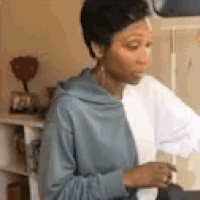 a woman in a blue hoodie is sitting on a treadmill in a living room .