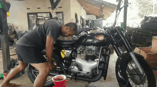a man is working on a black motorcycle with the number 2 on the side