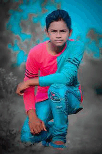 a young boy in a pink shirt and blue jeans is squatting down with his hands on his knees .