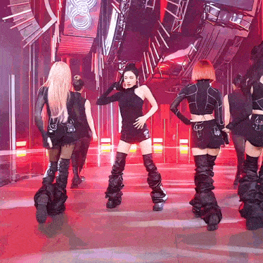 a group of women are dancing on a stage and one of them is wearing a black top with a turtleneck