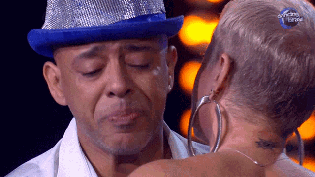 a man wearing a blue hat is crying next to a woman wearing hoop earrings and the words dancing brasil on the bottom