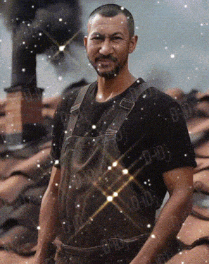 a man wearing overalls and a black shirt with the letters d-i-d on the bottom right