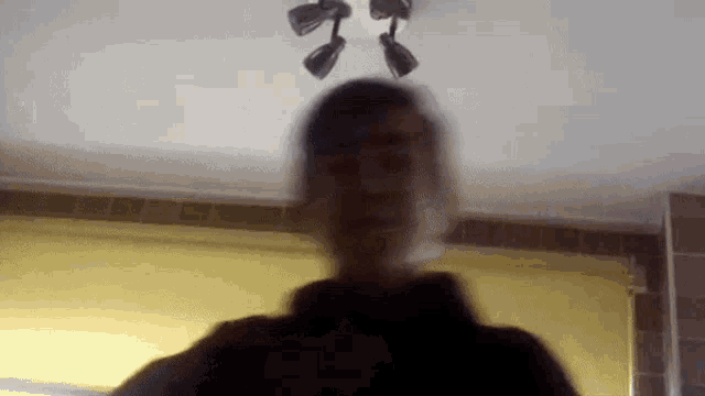 a blurry picture of a man taking a selfie in front of a ceiling light