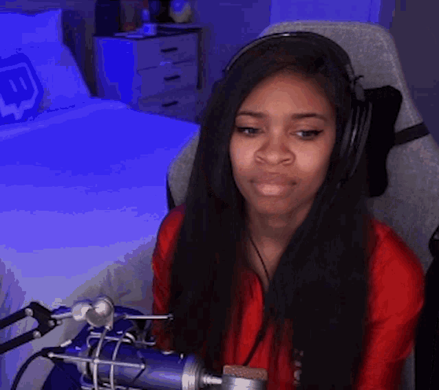 a woman wearing headphones is sitting in a chair in front of a microphone .