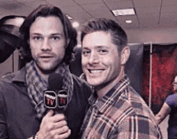 two men are standing next to each other holding microphones .