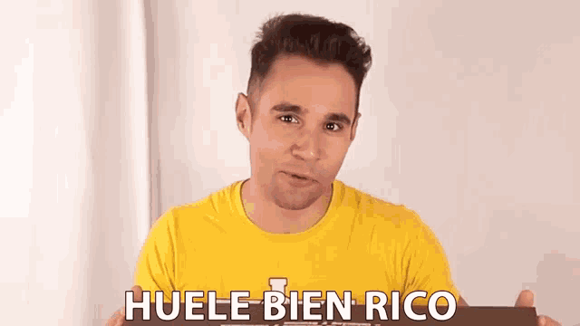 a man in a yellow shirt is holding a piece of paper that says huele bien rico