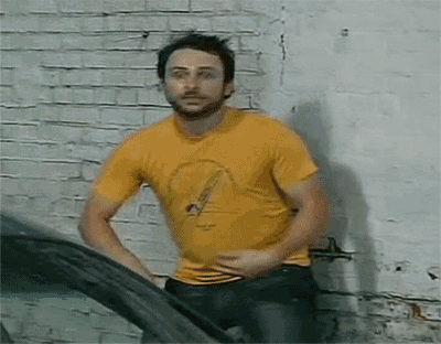 a man in a yellow t-shirt is standing next to a car .