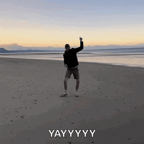 a man is dancing on a beach with the word yayyyy below him