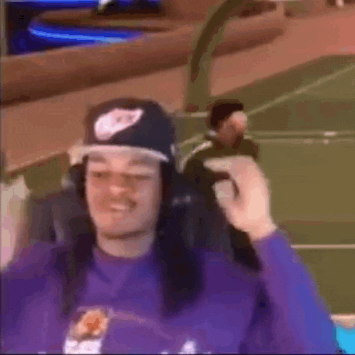 a man wearing a hat and headphones is sitting in a chair on a basketball court .