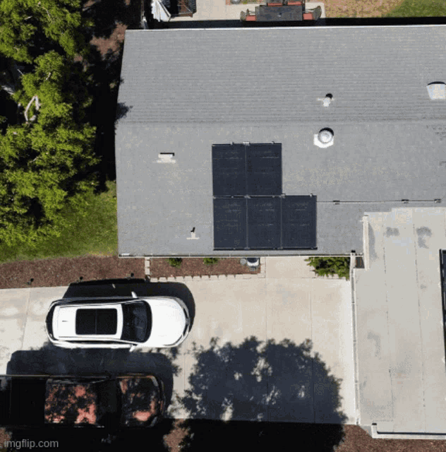 an aerial view of a house with solar panels on the roof and a car parked in the driveway
