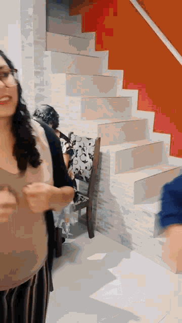 a woman is standing in front of a set of stairs and smiling