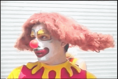 a man dressed as a clown with red hair and yellow gloves